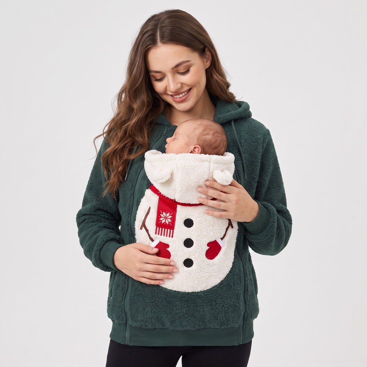 Mum wearing the Mistletot Snowman baby pouch hoodie, her baby asleep inside, facing her