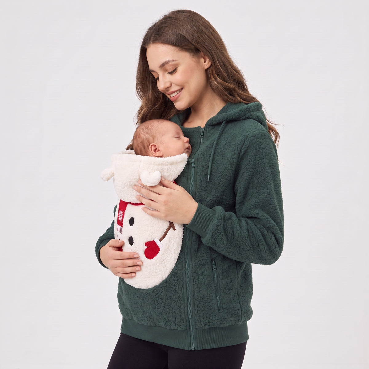 Mum in the Mistletot Snowman baby pouch hoodie, side view, smiling down at her sleeping baby
